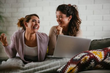 Kız arkadaşlar evde dizüstü bilgisayardan müzik dinlerler. Kızlar apartmanda eğleniyor..