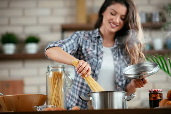 Young Woman Cooking in the kitchen. Woman cooking pasta dish.