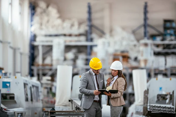 İşadamı ve işkadını fabrikadaki yeni iş projesini tartışıyor