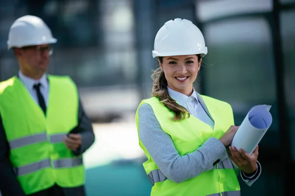 İnşaat alanının yanında durup projeyi tartışan gülümseyen mimarların portresi