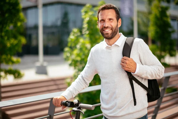 Young businessman outdoors. Handsome businessman with his electric scooter.