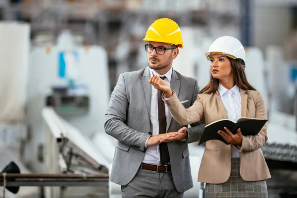 İşadamı ve işkadını fabrikadaki yeni iş projesini tartışıyor