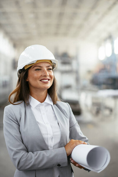 Portrait of an industrial woman engineer standing in a factory.