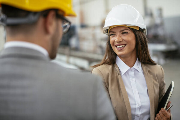 Businessman and businesswoman discussing new business project in factory
