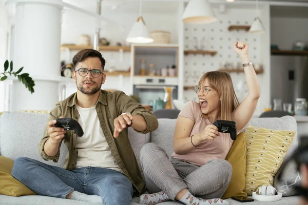 Beautiful young couple playing video games at home.