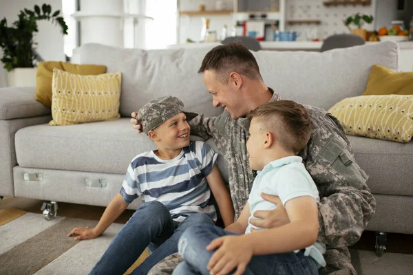 幸せな兵士は彼の家族と一緒に床に座っている 子供と一緒に家で楽しむ兵士 — ストック写真