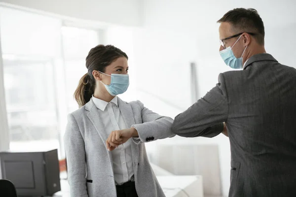 Ofiste tıbbi maskeli bir iş adamı ve iş kadını var. Covid-19 saatinde selamlar..