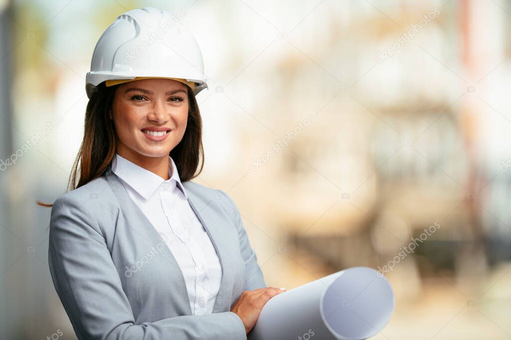 Portrait of beautiful female architect with blue prints in her hands.