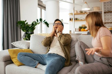 Erkek arkadaşı ve kız arkadaşı kanepede tartışıyor. Kızgın kadın erkek arkadaşına bağırıyor..