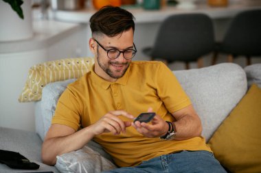 Adam kan şekerini glukometreyle ölçüyor. Genç adam kan şekeri seviyesini ölçüyor..