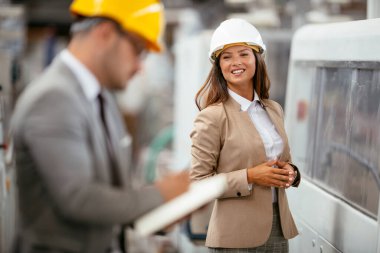 Fabrikadaki iş adamı ve iş kadını. Fabrika üretim hattında kalite kontrolde çalışan iki profesyonel insan..