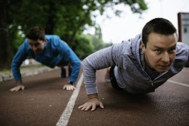 Yarış pistinde egzersiz yapan genç adamlar. Dışarıda antrenman yapan iki genç arkadaş..