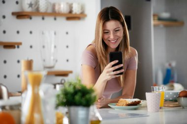 Mutfaktaki kadın. Mutfakta telefon kullanan güzel bir kadın..