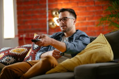 Evde televizyon izleyen yakışıklı bir adam. Evinde film izleyen sıradan bir adam..