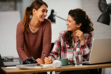 Açık uzay ofisinde konuşan ve gülen mutlu iş kadınları