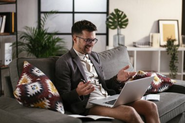 Evde pantolonsuz çalışan bir iş adamı. Genç adam video görüşmesi sırasında bilgisayarı kullanıyor..