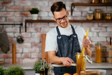 Mutfakta makarna hazırlayan yakışıklı adam. Lezzetli yemek pişiren adam..