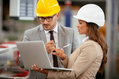 Fabrika müdürü ve mühendisi teftiş yapıyor. İş adamı ve işkadını üretim hattında.