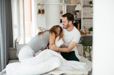 Çift evde eğleniyor, yastıklarla kavga ediyor.