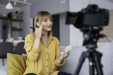 Kadın video kaydedicisi, kanalı için makyaj dersi kaydediyor. Sosyal medyada paylaşmak için makyaj dersi alan genç ve güzel bir kadın..