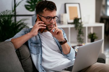 Adam evde çalışıyor, dizüstü bilgisayar kullanıyor.