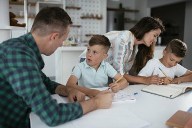 Ebeveynler çocuklara ev ödevlerinde yardım ediyorlar. Küçük çocuklar evde öğreniyor..