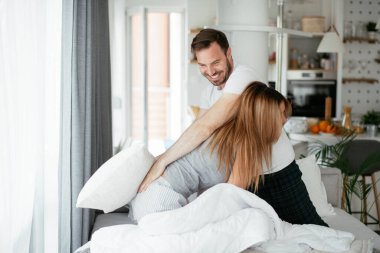 Çift evde eğleniyor, yastıklarla kavga ediyor.