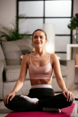 Evde egzersiz yapan genç bir kadın.