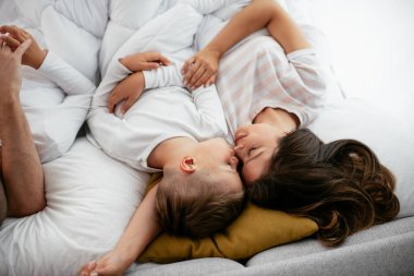 Anne ve oğlu yatakta yatıyor. Mutlu kadın ve oğlu yatakta dinleniyor..