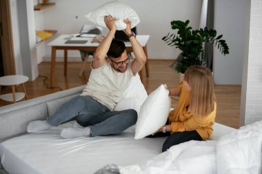 Erkek arkadaş ve kız arkadaş yatakta yastık kavgası yapıyor. Mutlu çift evde eğleniyor.