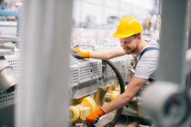 Üretim hattındaki fabrika işçisi. Fabrikada çalışan sarı kasklı adam..