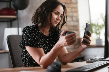 İş kadını ofiste çalışırken fren yaparken akıllı telefon kullanıyor.