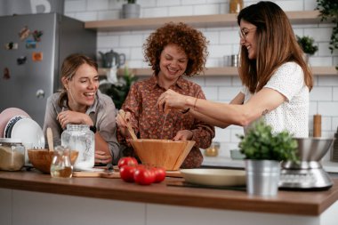 Kadın arkadaşlar mutfakta eğleniyor. Kardeşler birlikte yemek pişirir..