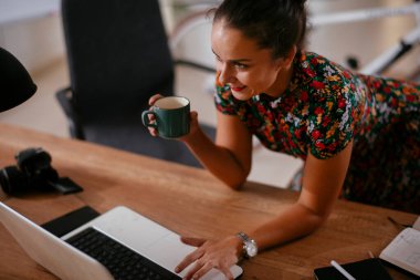 Ofiste bilgisayarla çalışan güzel genç bir iş kadını.
