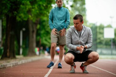 Yarış pistinde egzersiz yapan genç adamlar. Dışarıda antrenman yapan iki genç arkadaş..