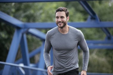 Genç adam şehirde koşuyor. Dışarıda antrenman yapan mutlu bir sporcu.