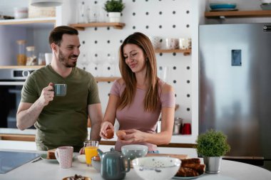 Genç çift evde sandviç yapıyor. Sevgi dolu çift mutfakta eğleniyor..