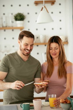 Genç çift evde sandviç yapıyor. Sevgi dolu çift mutfakta eğleniyor..