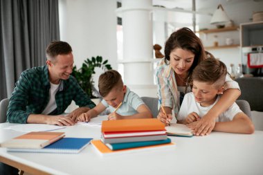 Ebeveynler çocuklara ev ödevlerinde yardım ediyorlar. Küçük çocuklar evde öğreniyor..