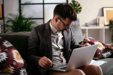 Evde pantolonsuz çalışan bir iş adamı. Genç adam video görüşmesi sırasında bilgisayarı kullanıyor..