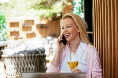 Takım elbiseli, şarap içen ve dizüstü bilgisayarla çalışan güzel bir iş kadını. İş kadını restoranda eğleniyor.