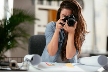 Mutlu genç bayan yönetici yaratıcı ofiste kamerayla fotoğraf çekiyor.. 