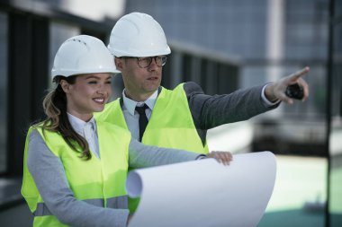 İnşaat alanının yanında durup projeyi tartışan gülümseyen mimarların portresi