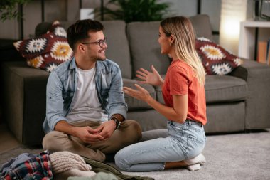 Genç çift yolculuk için hazırlanıyor, giysilerini seyahat çantasına koyuyorlar. Erkek arkadaş ve kız arkadaş geziye hazırlanıyor.