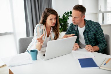 Evde dizüstü bilgisayar kullanan mutlu genç çift.