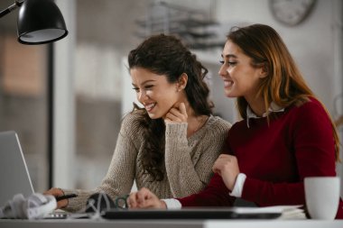 Açık uzay ofisinde konuşan ve gülen mutlu iş kadınları