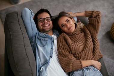 Genç ve sevgi dolu bir çift kanepede dinleniyor. Mutlu çift evde eğleniyor..