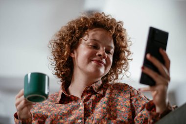 Telefonu kullanan genç bir kadın. Güzel kadın evde eğleniyor..