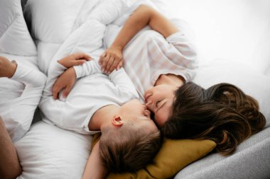 Anne ve oğlu yatakta yatıyor. Mutlu kadın ve oğlu yatakta dinleniyor..