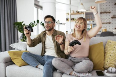 Karı koca oturma odasında joysticklerle oyun oynuyorlar. Sevgili çift evde video oyunu oynuyor..
